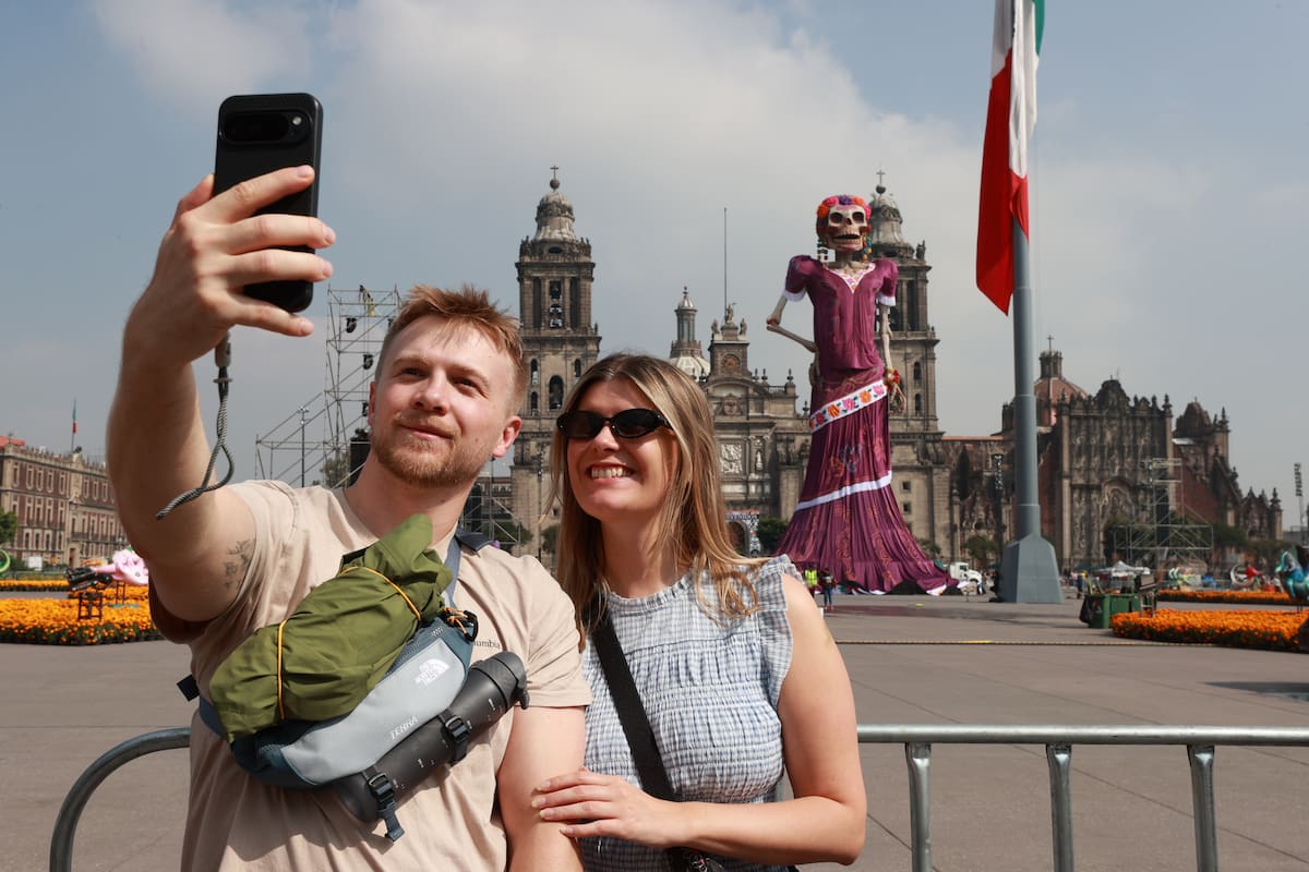 Personas posan junto a una catrina de 32 metros de altura, un montaje dedicado al artista José Guadalupe Posada, este viernes en el Zócalo de Ciudad de México (México) EFE/ Mario Guzmán