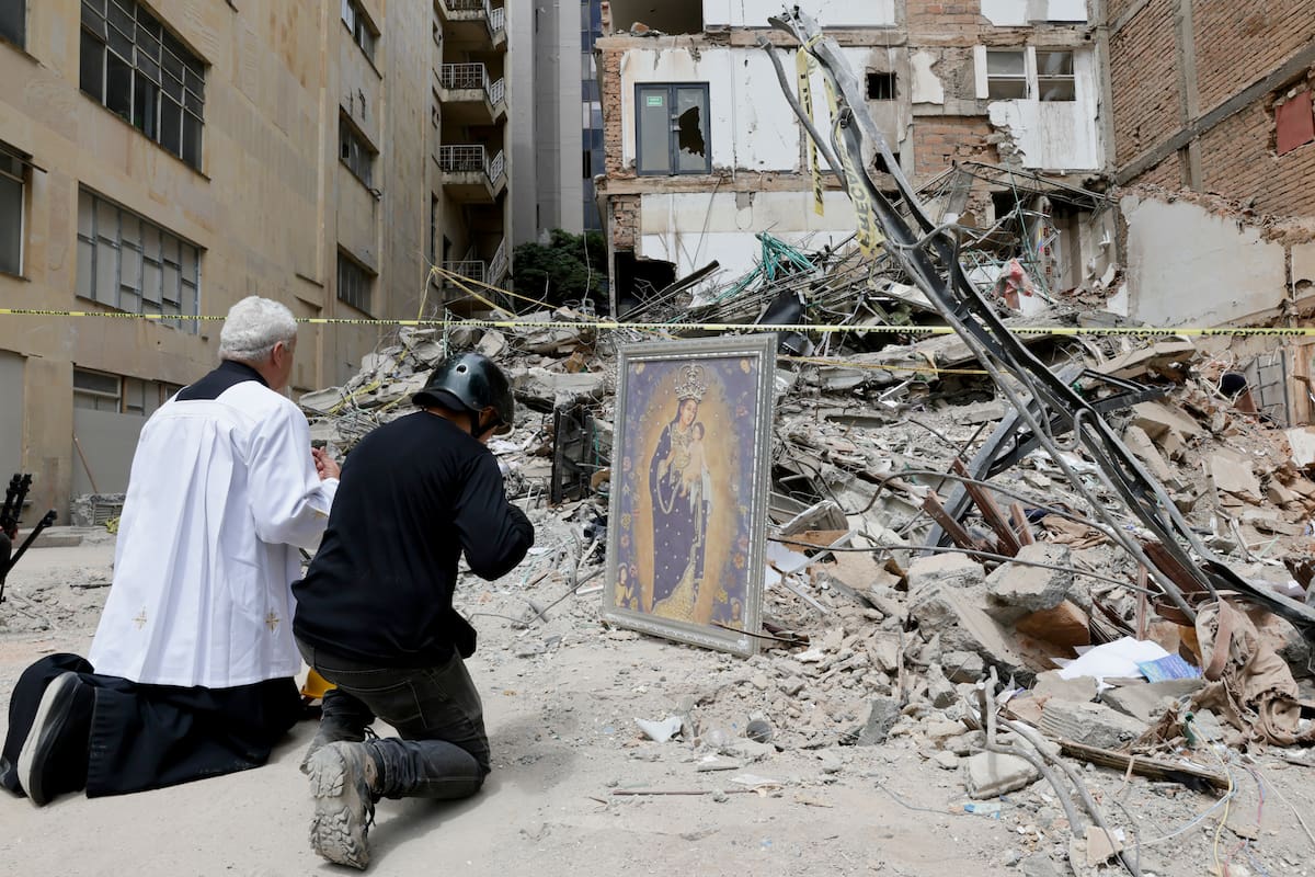 FOTODELDÍA AME9126. PEREIRA (COLOMBIA), 14/08/2026.- El padre Nelson Giraldo Mejía ora por las víctimas del terremoto de magnitud 7,4 ocurrido el pasado lunes, frente a los escombros del edificio Santiago Londoño, con una réplica de la Virgen de Nuestra Señora de la Pobreza, este viernes en Pereira. (Colombia). EFE/ Carlos Ortega