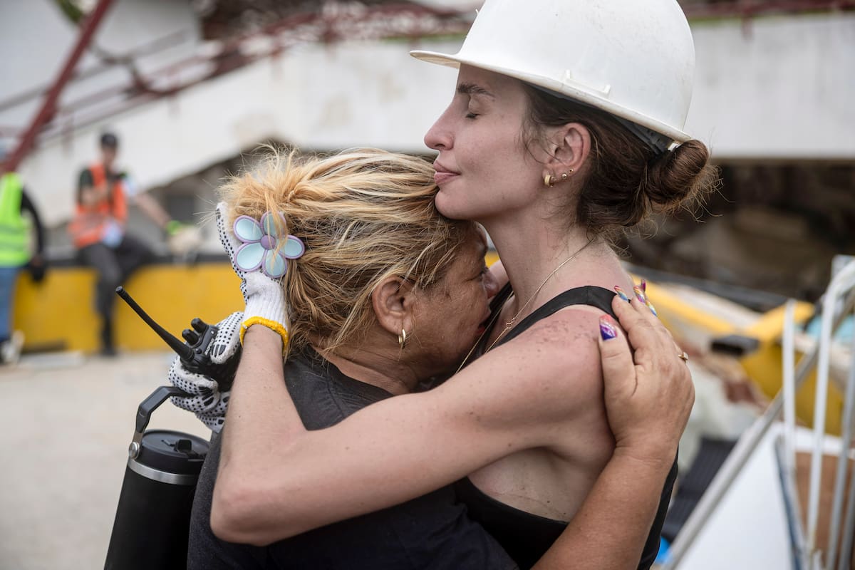 AME7137. CARABALLEDA (VENEZUELA), 03/07/2026.- Una rescatista abraza a una mujer durante la jornada de búsqueda por los terremotos en Venezuela, este viernes en Caraballeda, La Guaira (Venezuela). Un operativo de rescatistas locales e internacionales buscan señales de vida para comenzar un complejo rescate del niño que se quedó atrapado en los escombros del edificio Taihiti en la localidad de Caraballeda, en la región costera, el epicentro de la devastación del doble terremoto de la semana pasada. EFE/ Miguel Gutiérrez