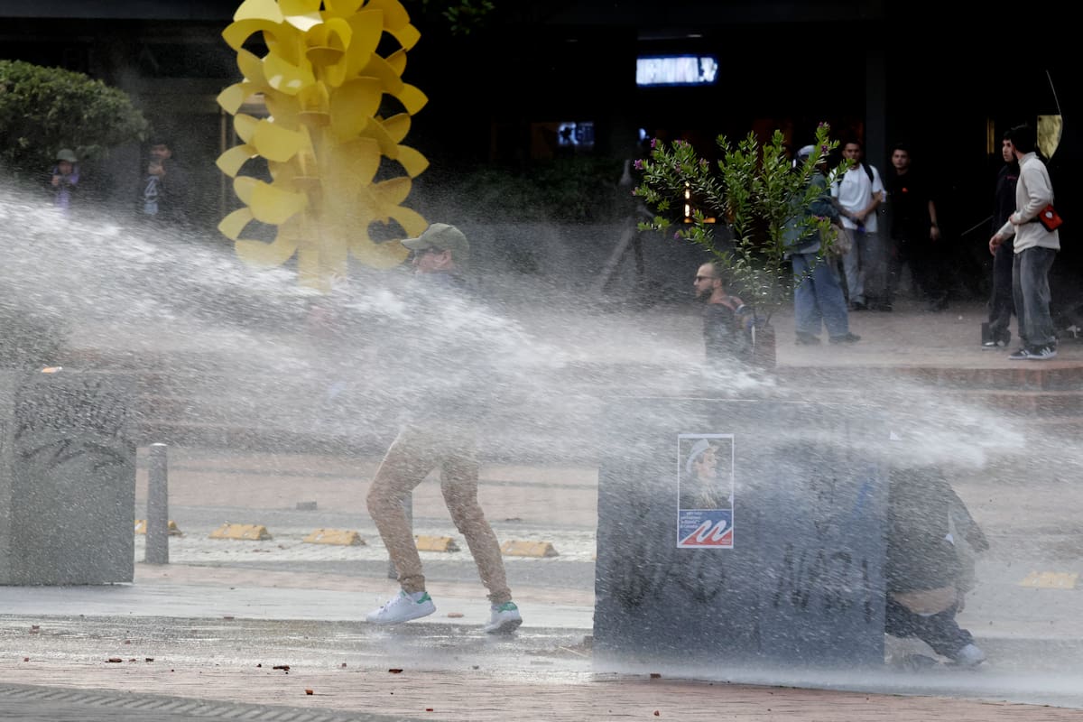 AME7339. BOGOTÁ (COLOMBIA), 18/10/2026.- Personas se enfrentan con integrantes de la Unidad Nacional de Antidisturbios (Unadi) durante una manifestación ante la retirada de al menos 30 afiches, fotografías y objetos relacionados con los movimientos feministas y LGBTI, las víctimas de la violencia política y el acuerdo de paz firmado en 2016 con las FARC del Museo Nacional, este domingo en Bogotá (Colombia). EFE/ Carlos Ortega