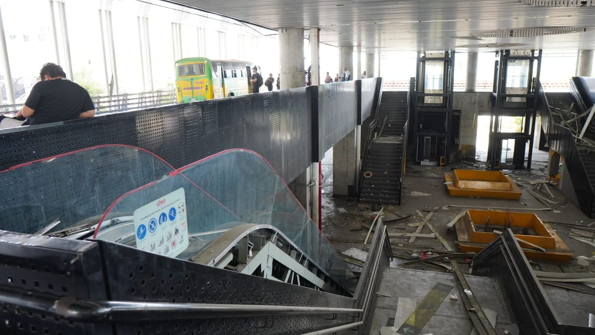 La escalera eléctrica del Portal de Piedecuesta quedó desarmada y con el vidrio de protección volcado sobre la estructura. Al fondo, los dos ductos de los ascensores permanecen vacíos mientras usuarios esperan el bus en la plataforma superior. Foto: Marco Valencia / Vanguardia