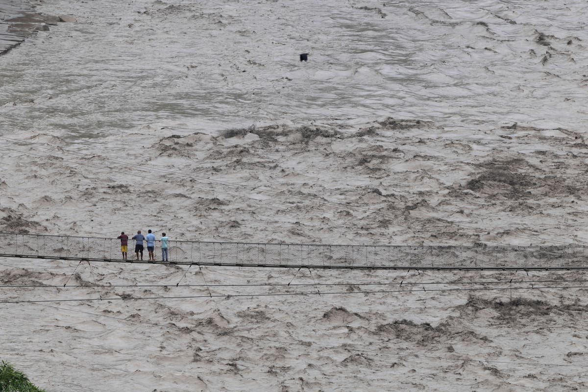 Los vecinos observan como sube el nivel del río Trishuli desde un puente peatonal, en el distrito de Dhading (Nepal). //EFE - NARENDRA SHRESTHA.
