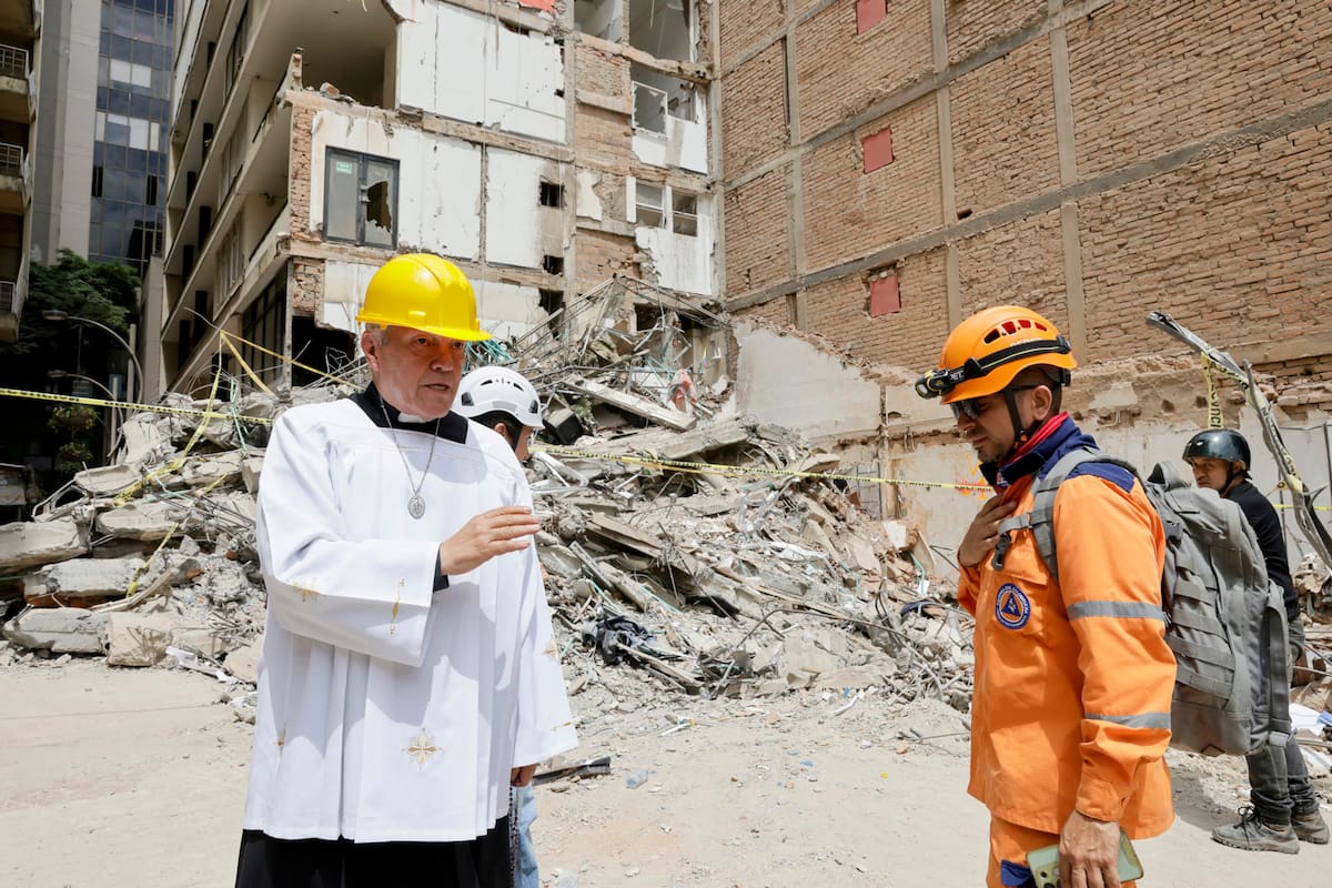 El padre Nelson Giraldo Mejía (i) ora por las víctimas del terremoto de magnitud 7,4 ocurrido el pasado lunes, frente a los escombros del edificio Santiago Londoño, este viernes en Pereira. (Colombia). EFE/ Carlos Ortega