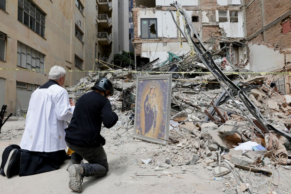 El padre Nelson Giraldo Mejía ora por las víctimas del terremoto de magnitud 7,4 ocurrido el pasado lunes, frente a los escombros del edificio Santiago Londoño, con una réplica de la Virgen de Nuestra Señora de la Pobreza, este viernes en Pereira. (Colombia). EFE/ Carlos Ortega