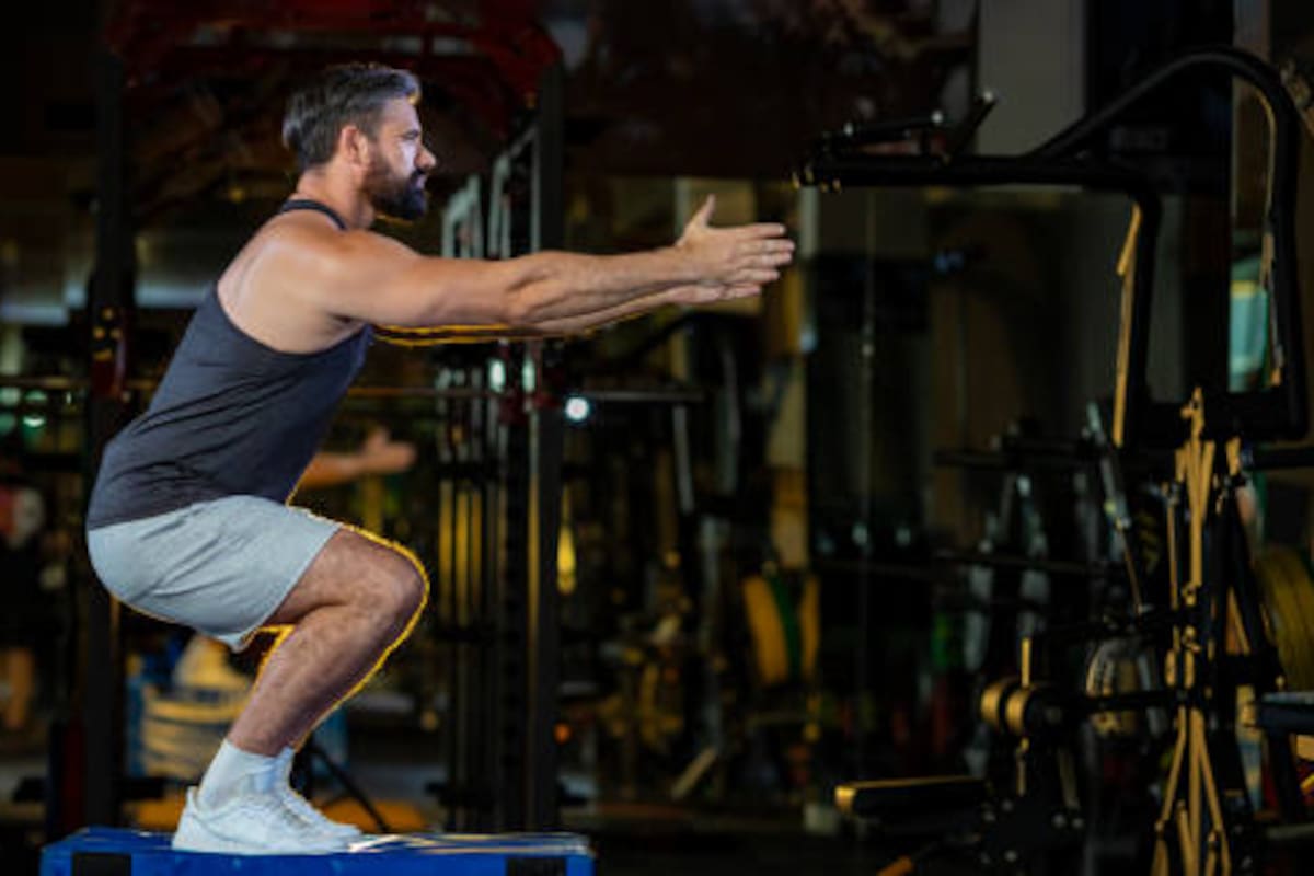 Un hombre haciendo sentadillas en un gimnasio.