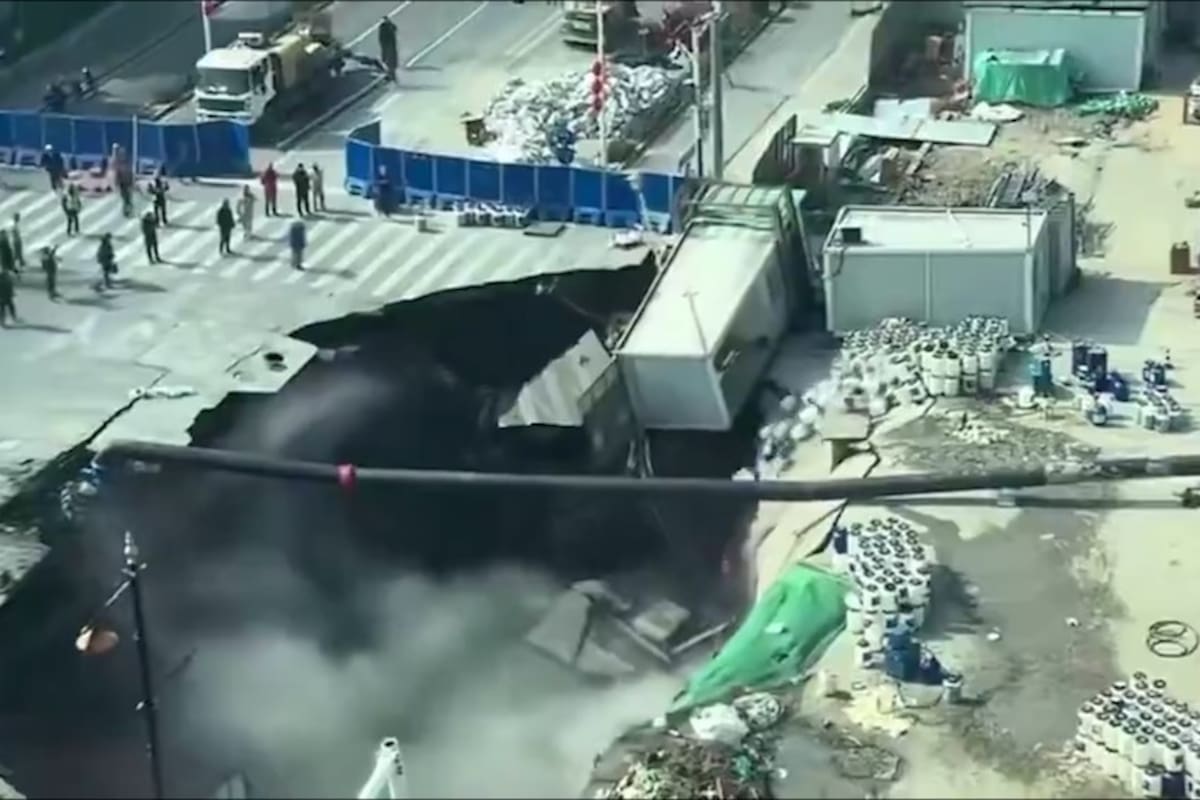 Una vista aérea muestra el impactante colapso de una calle en Shanghái, donde un camión ha caído parcialmente en un enorme socavón mientras transeúntes observan la escena. (Captura de video)