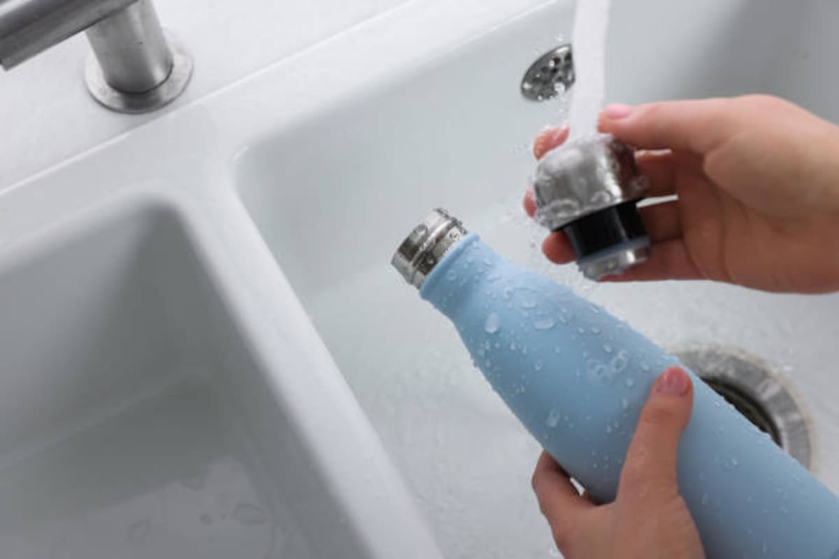 Una persona lavando un termo metálico.