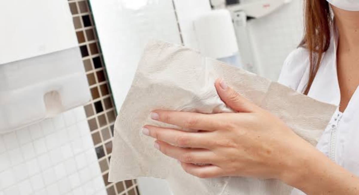 Una mujer secándose las manos con una toalla de papel.