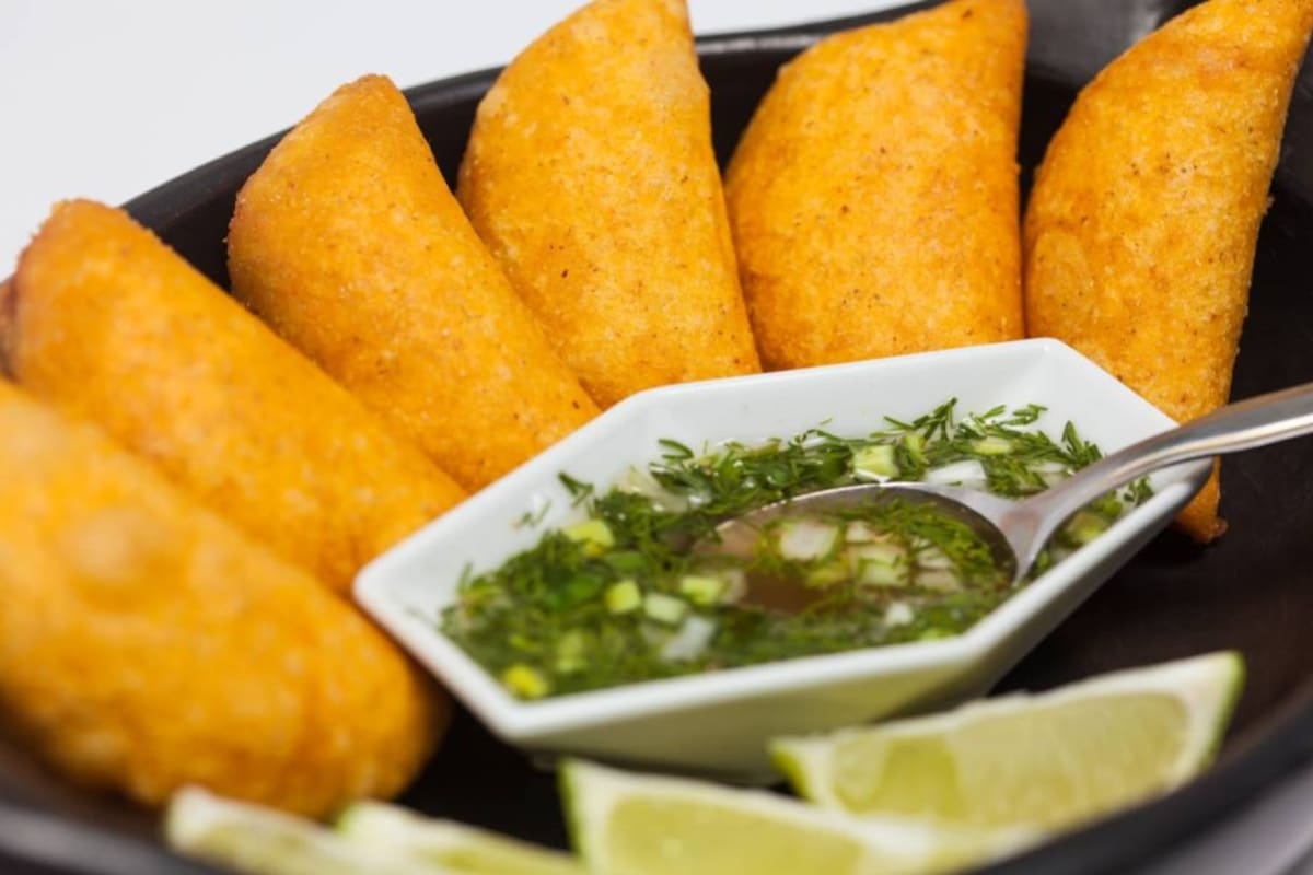 Typical Colombian empanadas served with spicy sauce on traditional black ceramic dish