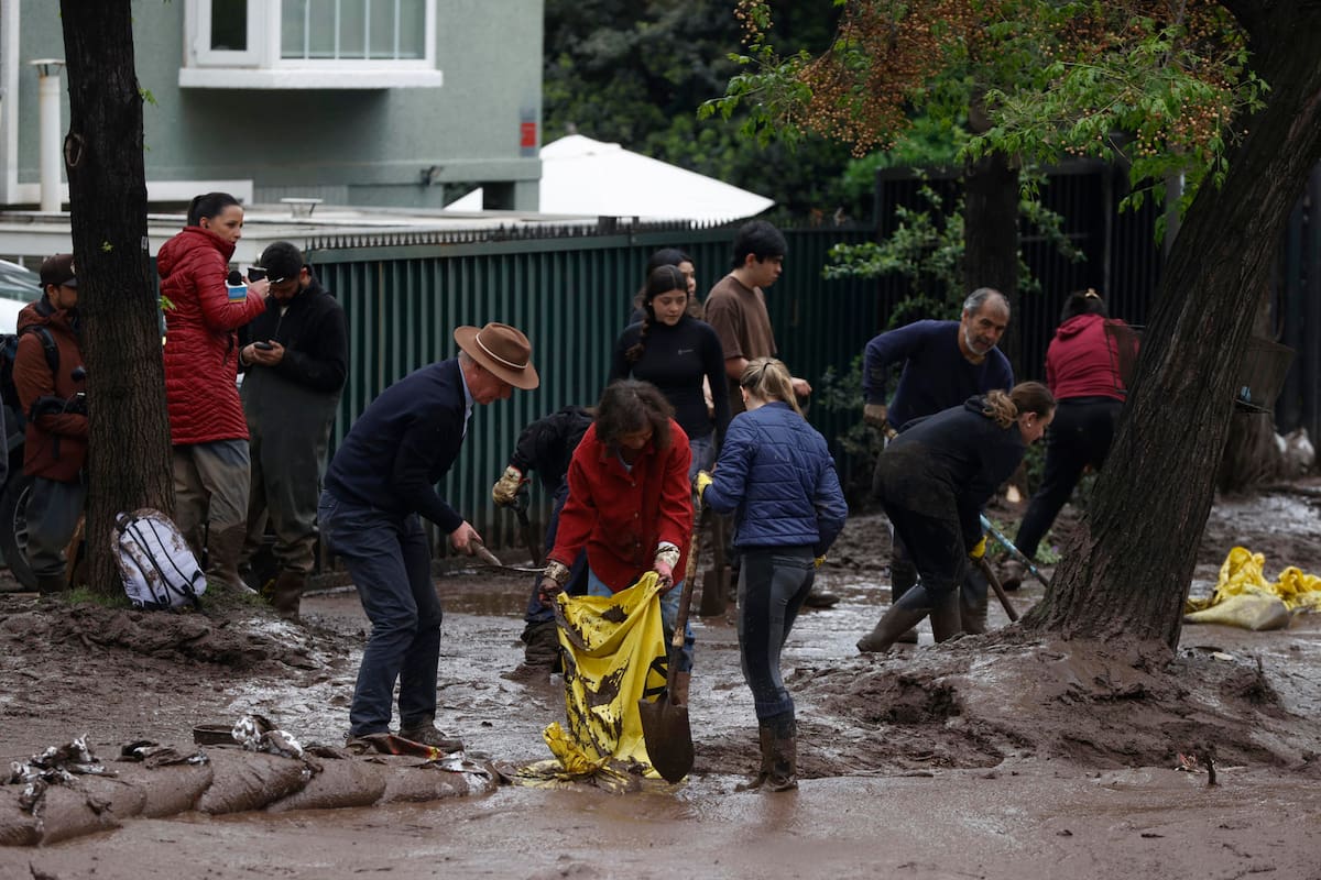 Personas trabajan en la remoción de lodo tras el paso de un aluvión en la comuna de Las Condes este viernes, en Santiago (Chile). Un aluvión por intensas lluvias que afectó a la comuna Las Condes, en el este de Santiago, y generó el arrastre de vehículos y buses en las calles, dejó 6 personas lesionadas y 600 hogares evacuados, informó el ministro del Interior de Chile, Claudio Alvarado. EFE/ Elvis González