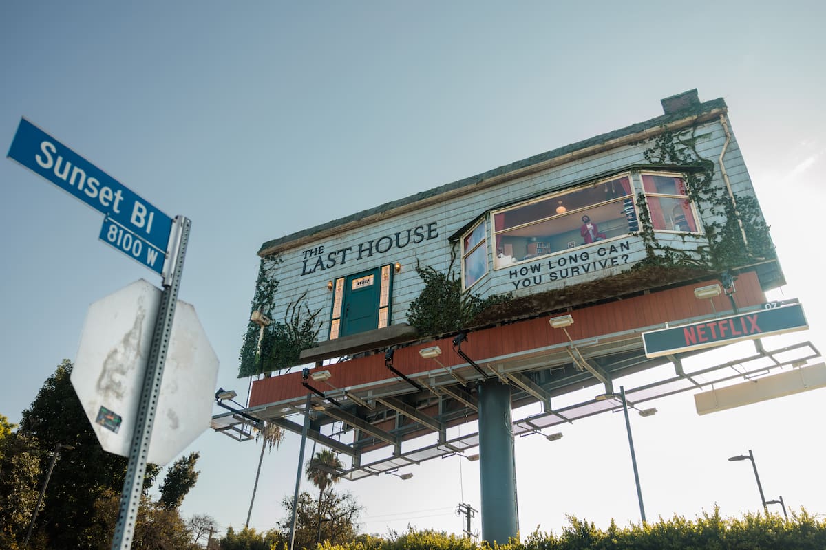 Fotografía de este jueves cedida por Netflix donde se muestra una valla publicitaria, que incluye una estructura que recrea parte de una vivienda, donde un intérprete permanecerá entre el 6 y el 8 de agosto, para promocionar 'The Last House', la nueva película de Greta Lee y Wagner Moura, instalada en el bulevar Sunset, una de las zonas más transitadas de Los Ángeles, California.