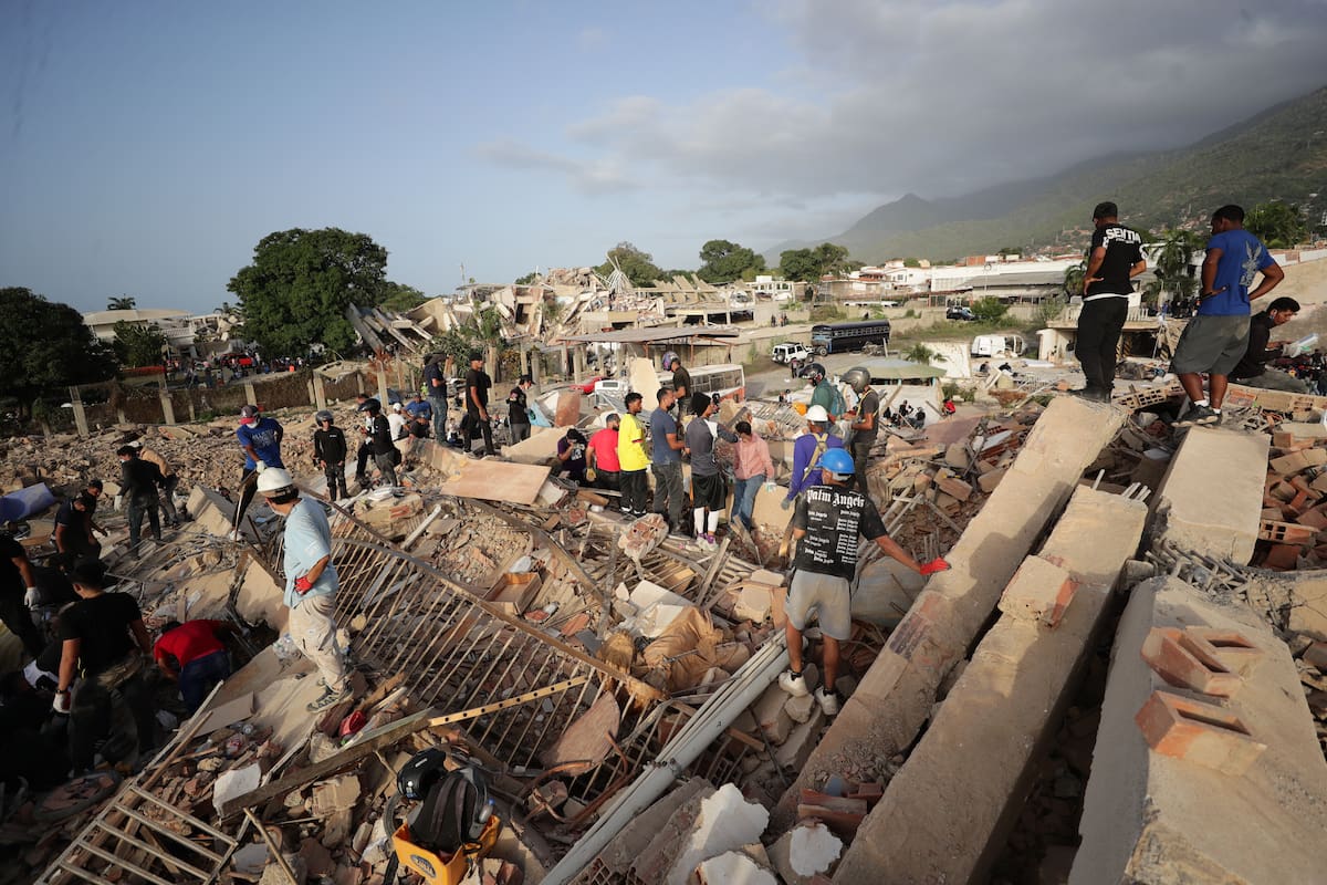 AME5030. LA GUAIRA (VENEZUELA), 26/06/2026.- Personas realizan labores de búsqueda en una zona afectada por un terremoto, este viernes en La Guaira (Venezuela). Venezuela afrontó su tercer día de emergencia con apoyo de brigadas de rescate de nueve países, entre ellos Estados Unidos y España, que se han sumado a las labores de búsqueda de supervivientes o fallecidos, tras el doble terremoto del pasado miércoles que deja al menos 920 muertos y 3.360 heridos, según cifras oficiales. EFE/ Ronald Peña R