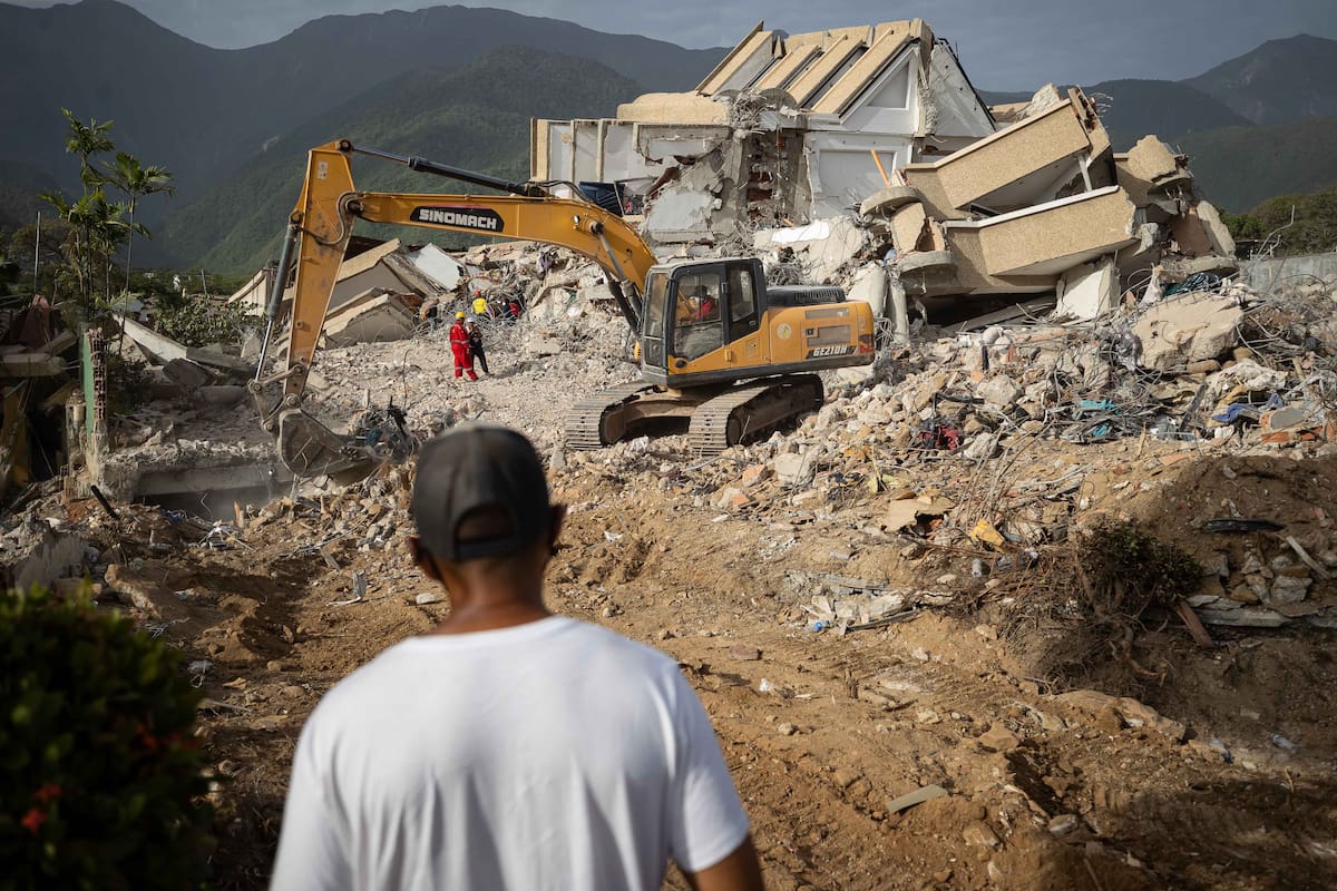 FOTODELDÍA AME7643. LA GUAIRA (VENEZUELA), 05/07/2026.- Una persona observa maquinaria pesada removiendo escombros este domingo, en La Guaira (Venezuela). A las calles de La Guaira, la zona devastada por el doble terremoto de Venezuela, han llegado en las últimas horas decenas de máquinas amarillas para retirar escombros y ayudar a acelerar las labores de recuperación de cadáveres. EFE/ Ronald Peña R